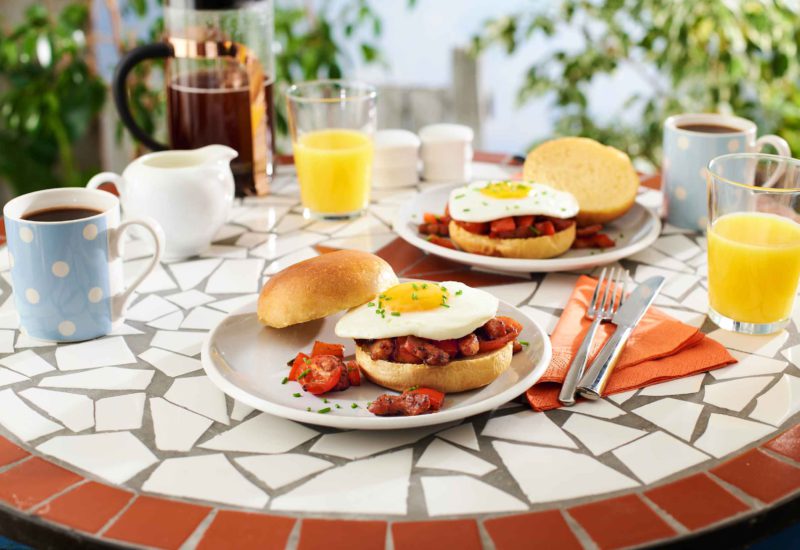 A table with plates and breakfast burgers in an outdoor setting